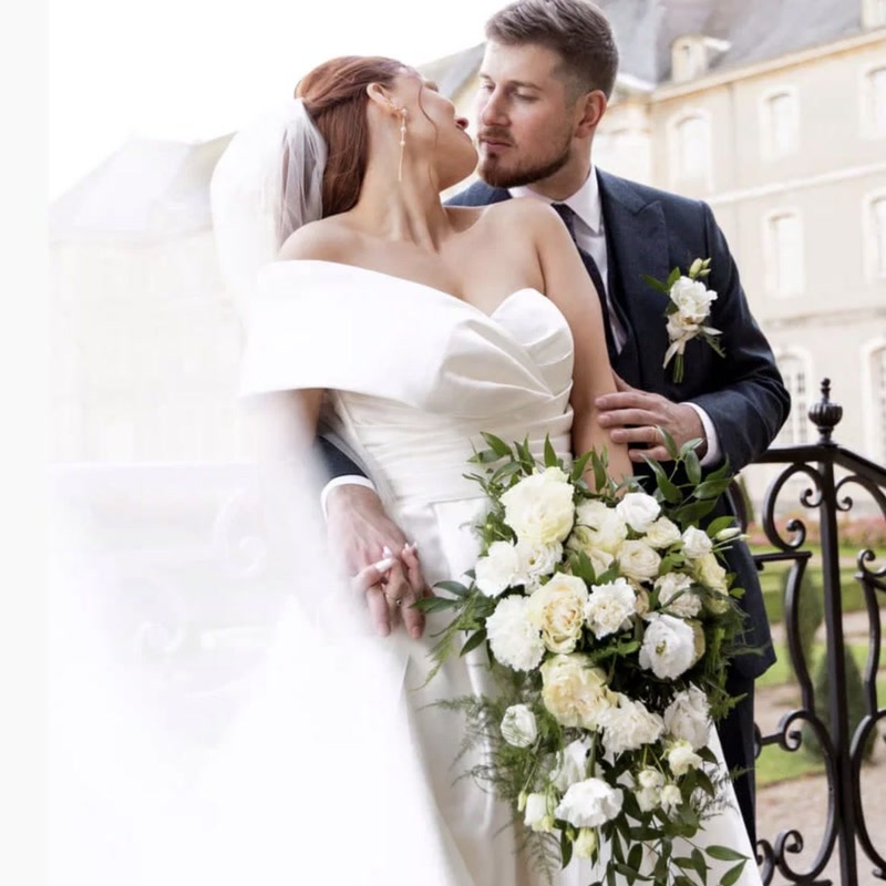 Mariés et bouquet de mariée blanc devant un château