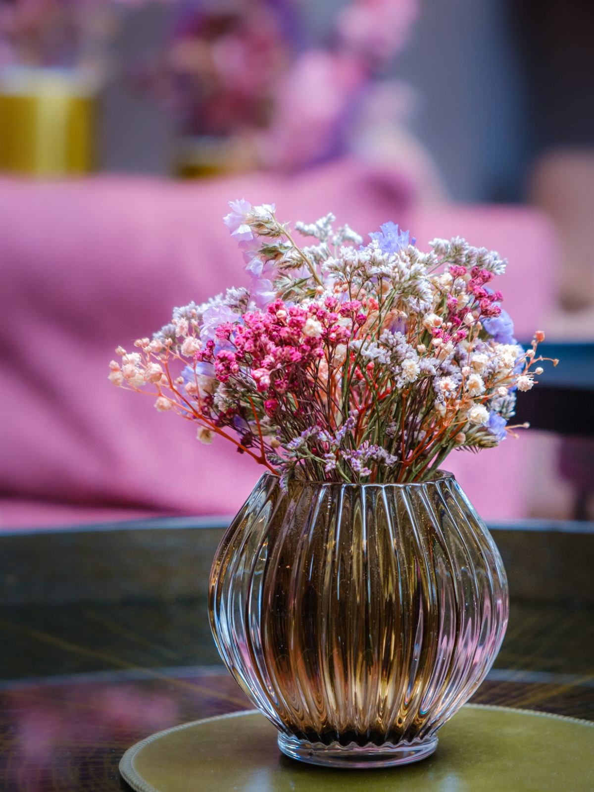 Bouquet de fleurs séchées dans un vase en verre ambré, sur une table basse