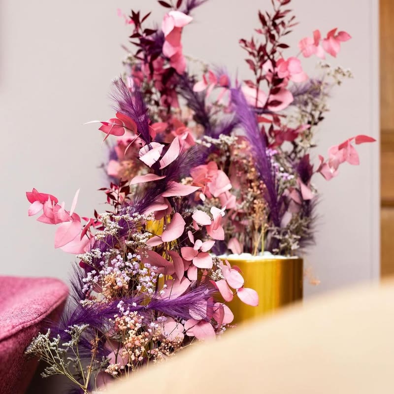 Compositions de fleurs stabilisées roses et violettes dans des vases dorés