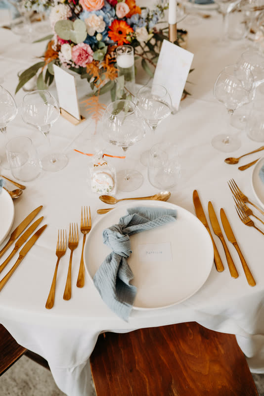 Art de la table : assiette, couverts dorés et serviette bleue