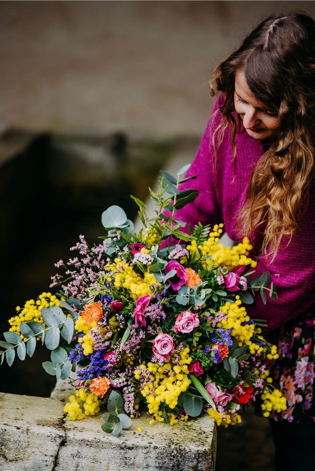 Pauline Wilmouth posant un bouquet de mimosa, roses et eucalyptus