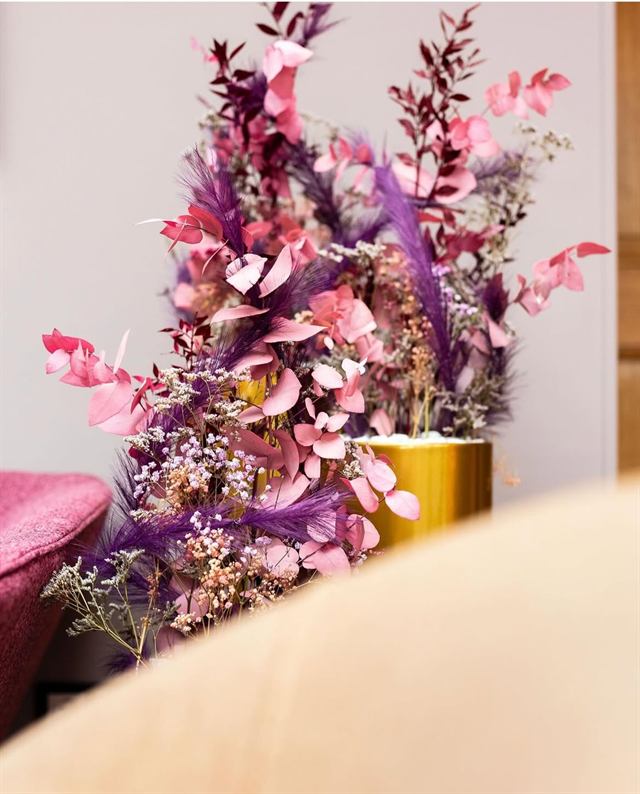 Compositions de fleurs stabilisées roses et violettes dans des vases dorés