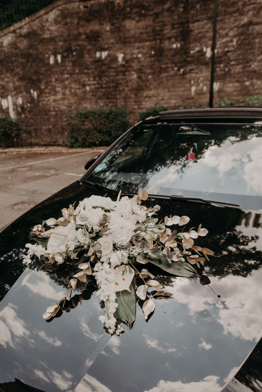 Voiture des mariés décorée d'une composition de fleurs blanches